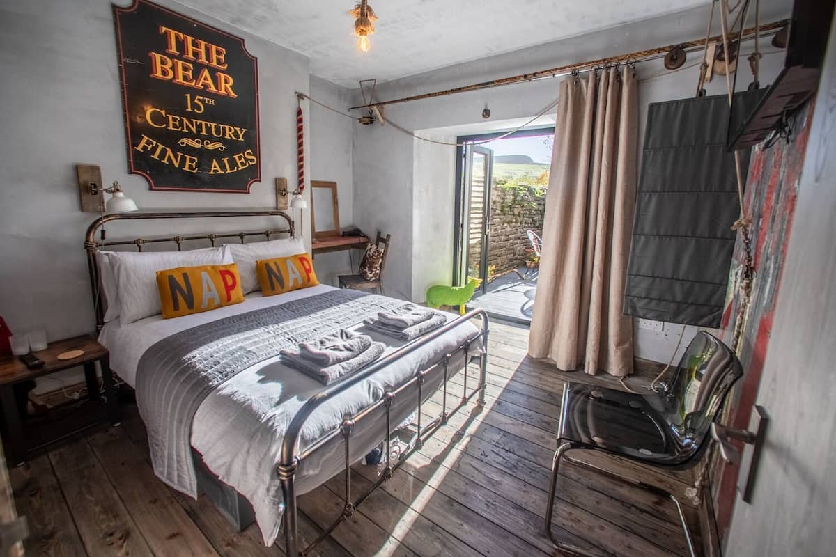 A bedroom with a bed, a nightstand, a chair, a window, and a sign on the wall.
