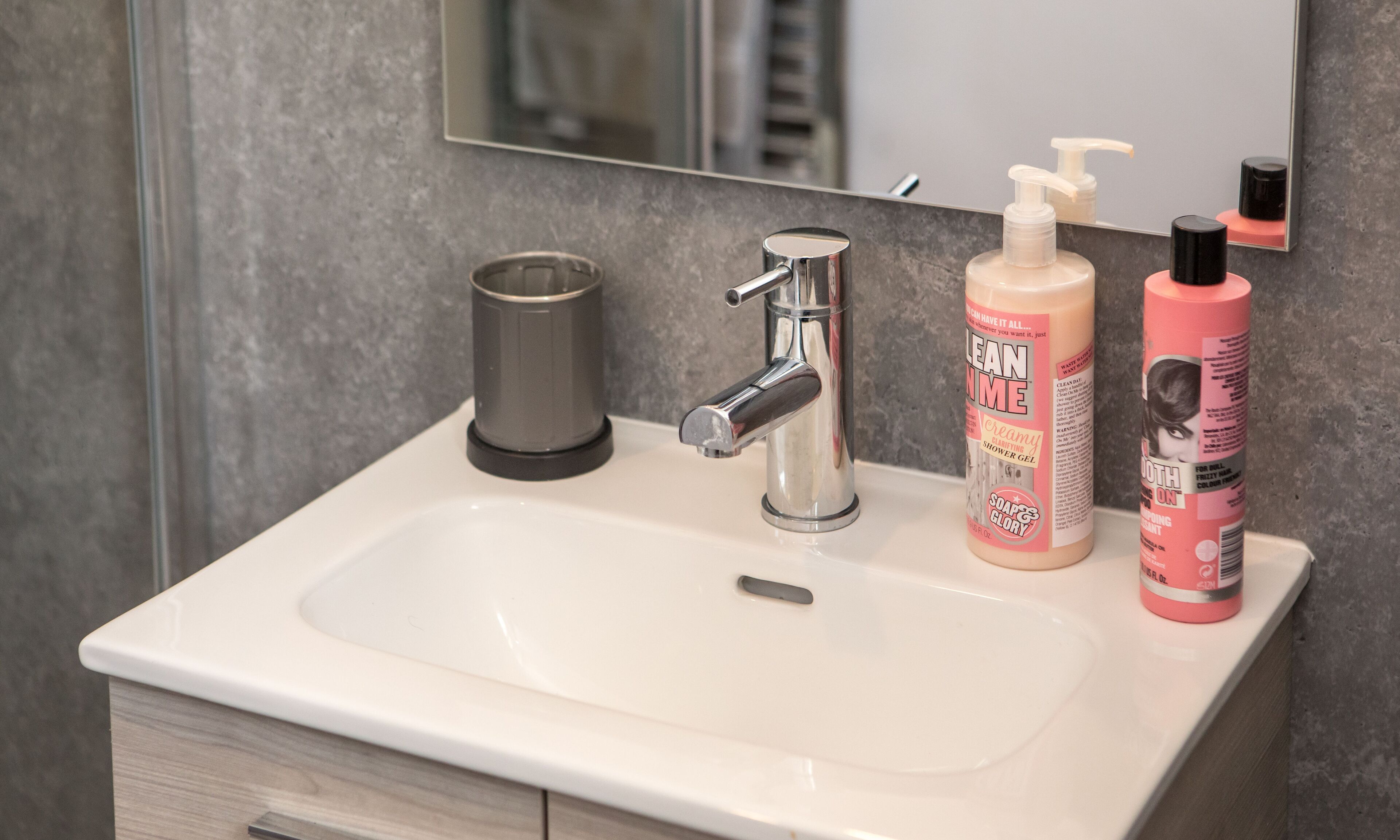 A bathroom sink with a modern faucet, a soap dispenser, and a bottle of shower gel.