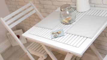 A white table with a glass jar containing a key and a lock, a white chair, and a white kettle on a white tablecloth.