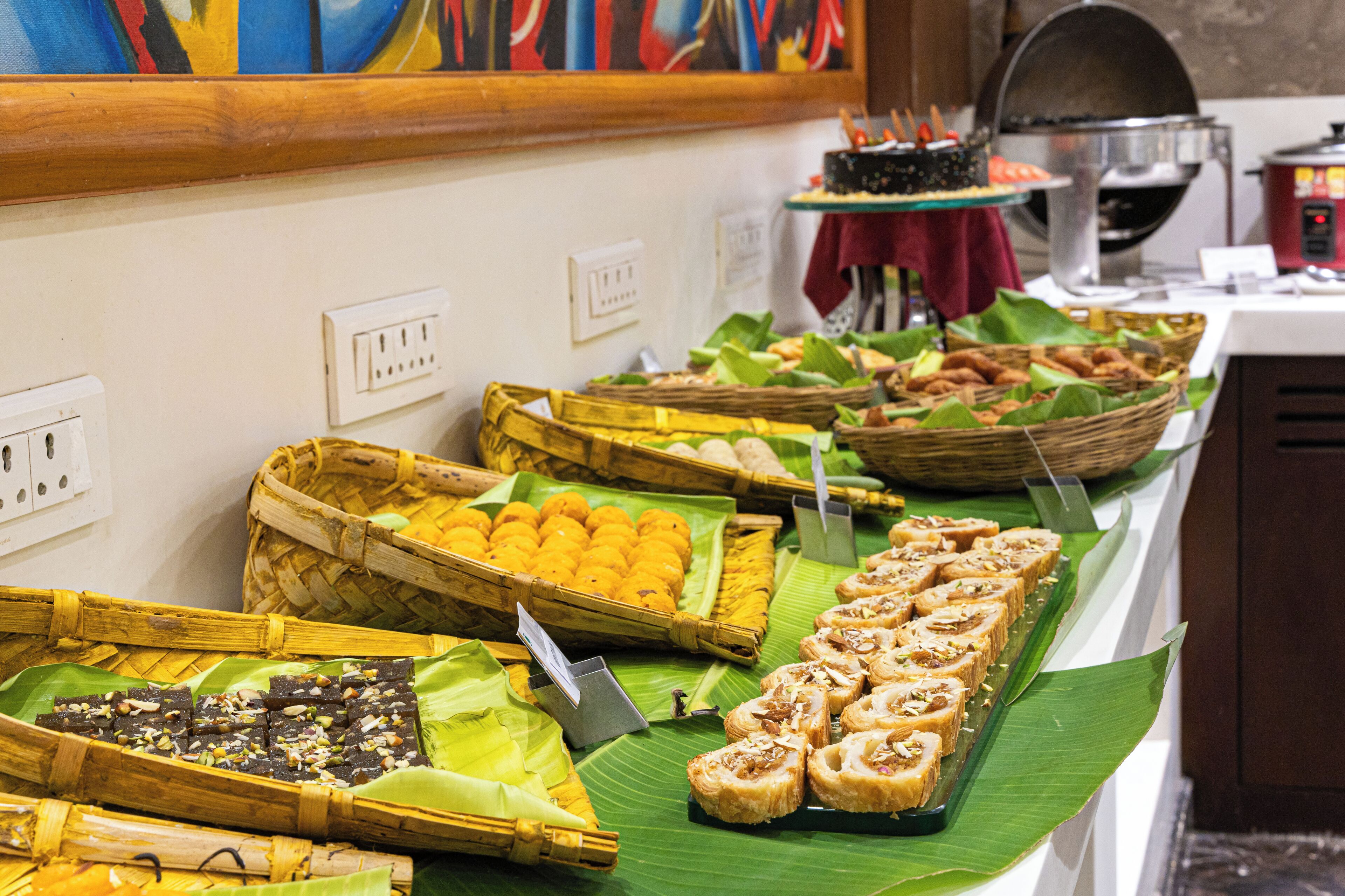 A buffet with various food items arranged on banana leaves and in baskets.
