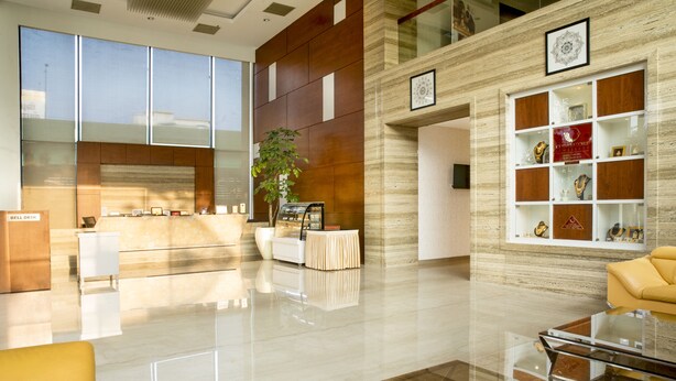 A modern lobby with a reception desk, a seating area with a glass table, and a display of trophies on the wall. - CJ Pallazzio (Salem)