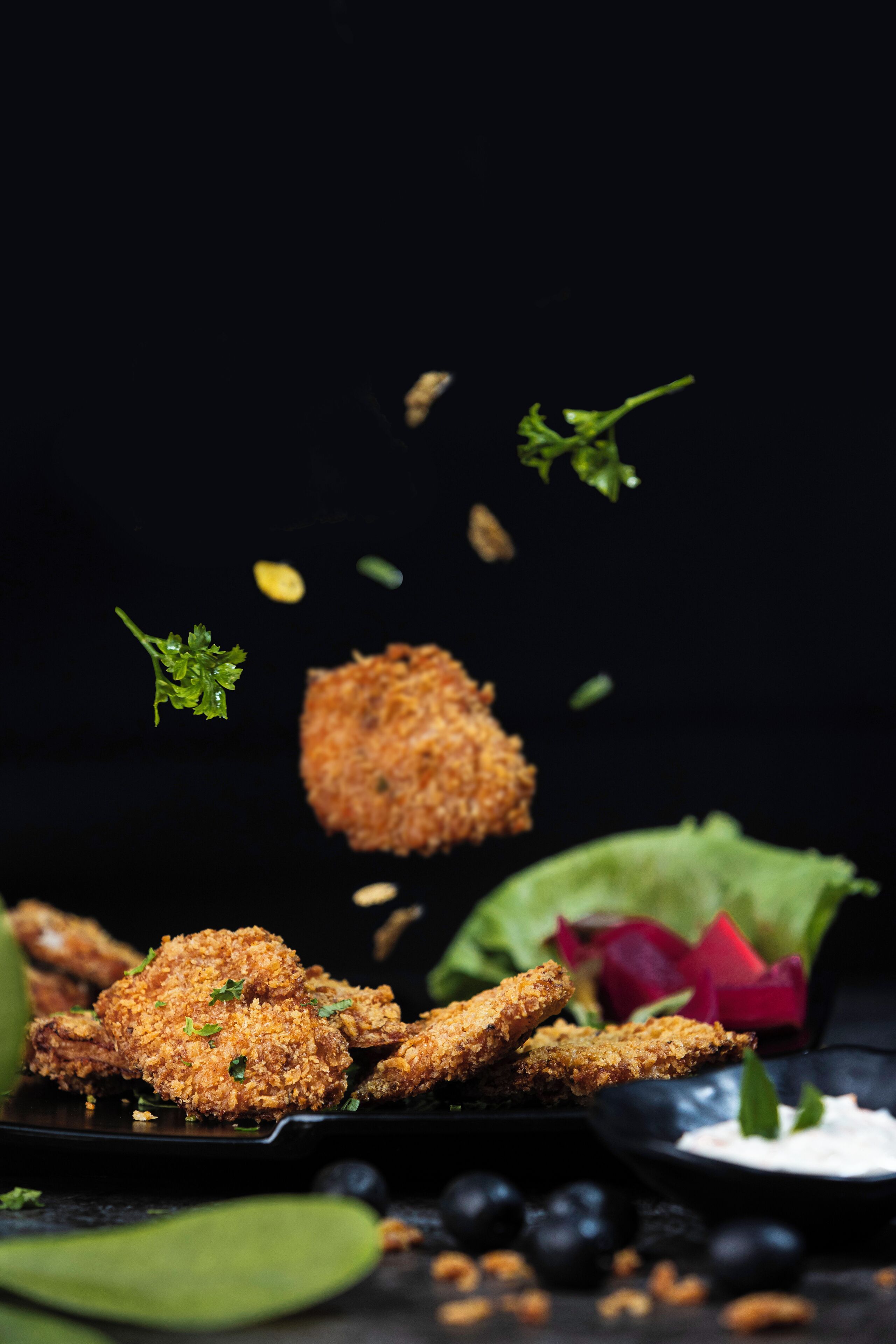 Un plato de alitas de pollo fritas con salsa para mojar y una ensalada.
