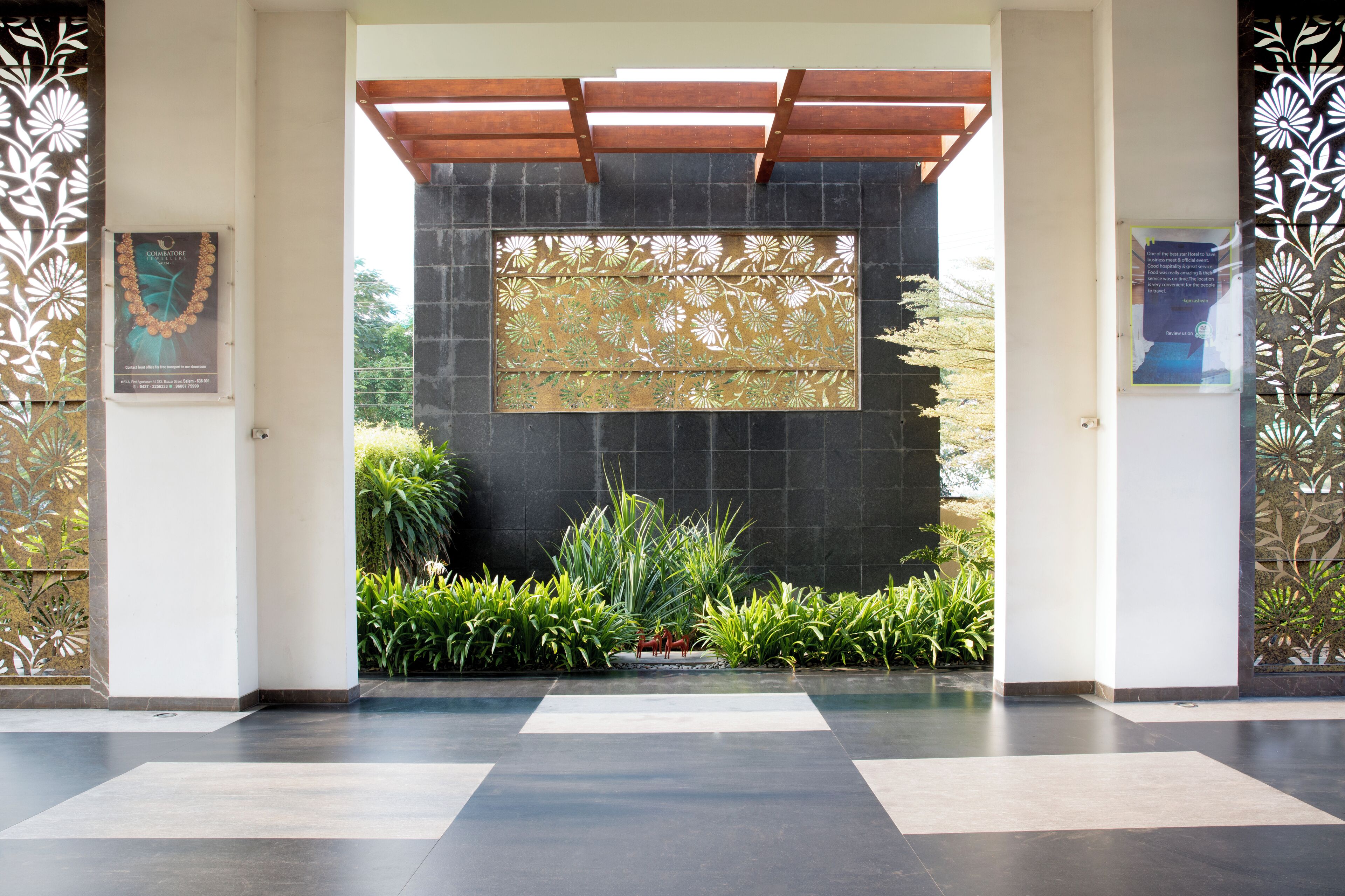 A modern entrance with a stone wall, a wooden pergola, and decorative panels.