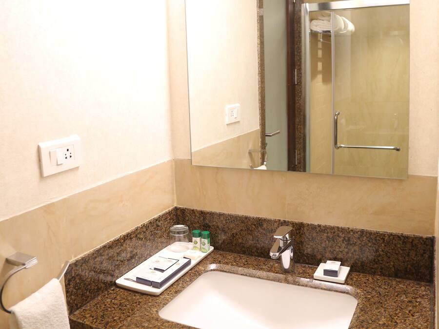 A bathroom with a granite countertop, a white sink, a mirror, and a towel hanging on a rack.
