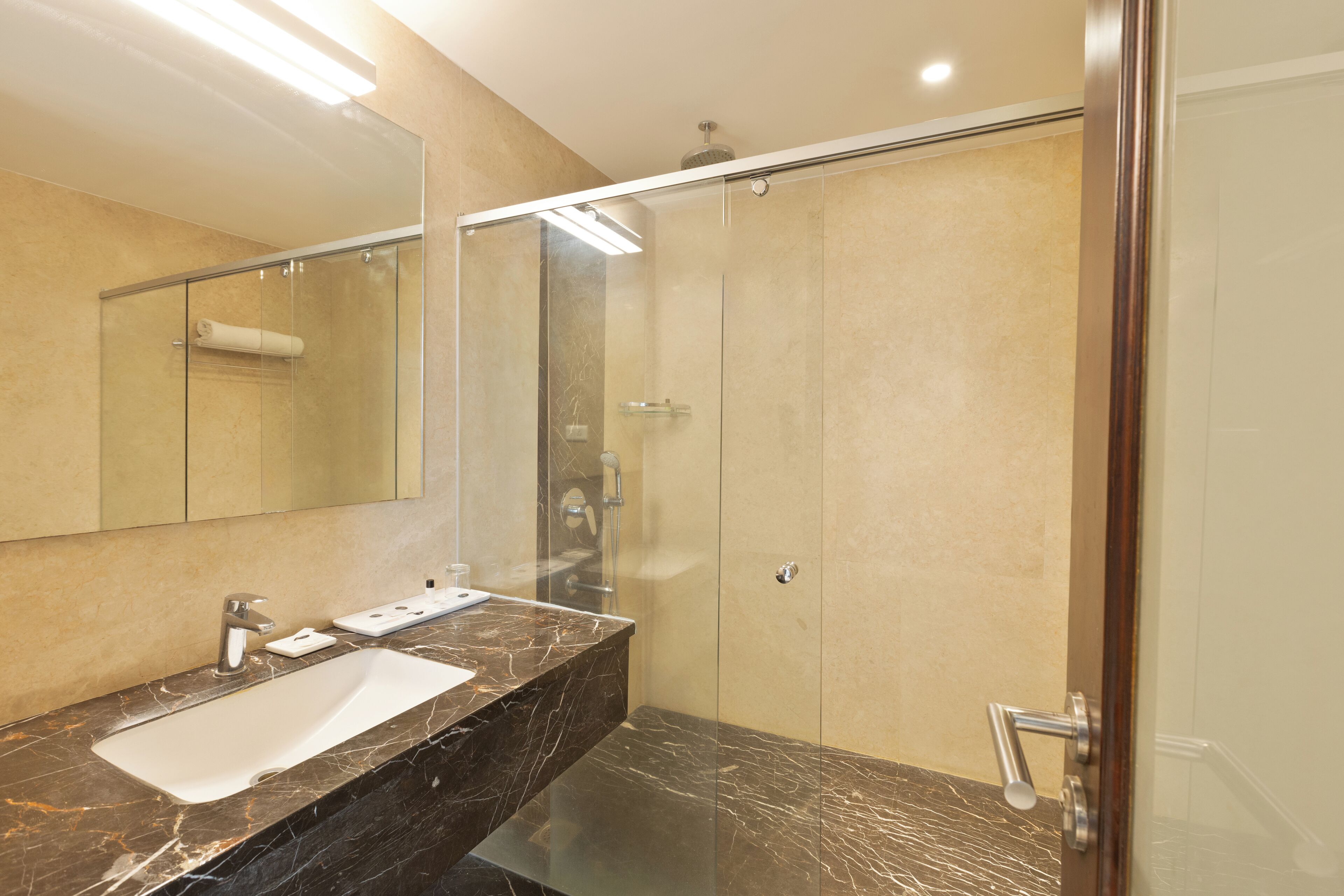 A modern bathroom with a glass-enclosed shower, a marble sink, and a large mirror.