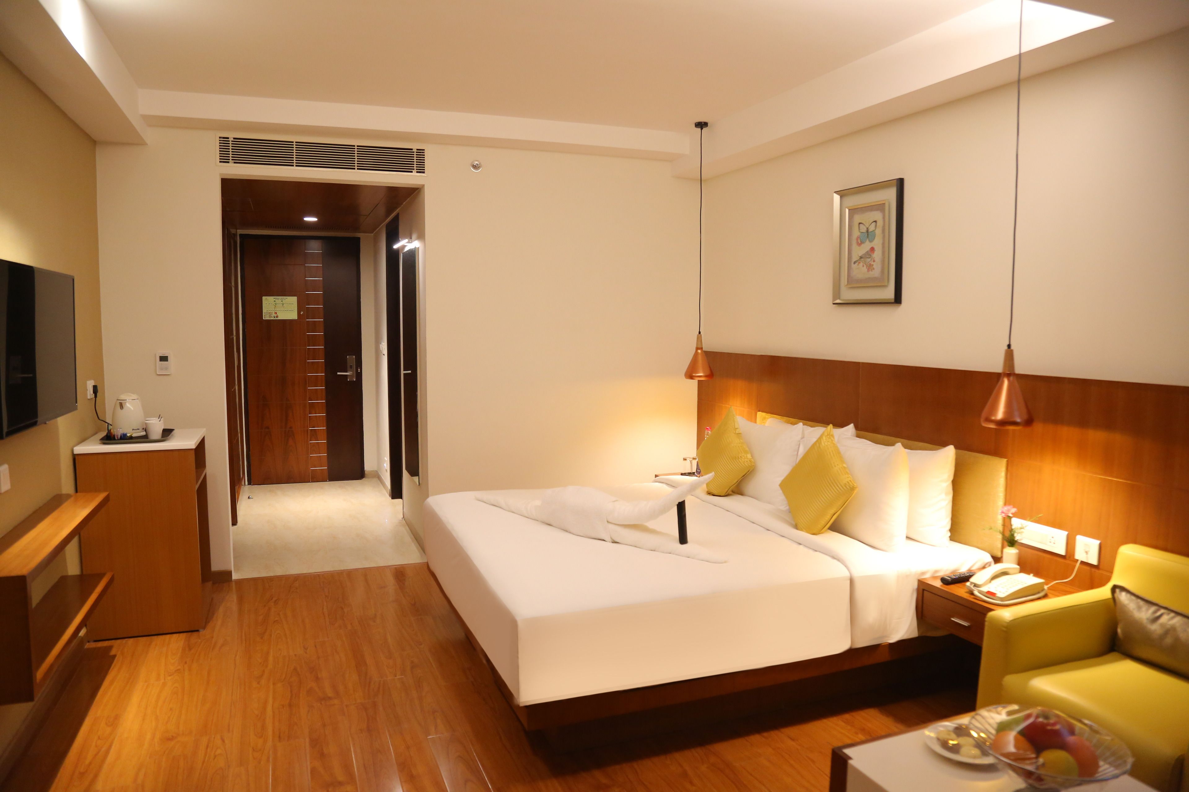 A hotel room with a bed, bedside table, chair, and a television.