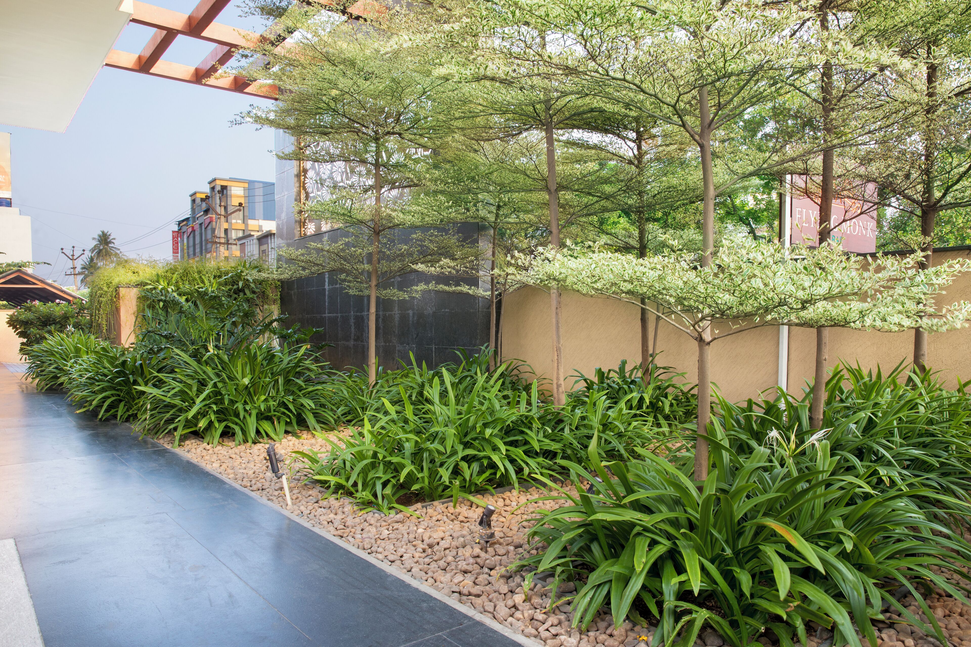Un sendero bordeado de plantas y árboles verdes, que conduce a un edificio de diseño moderno.