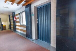 Un pasillo con extintor, una puerta cerrada y una ventana.