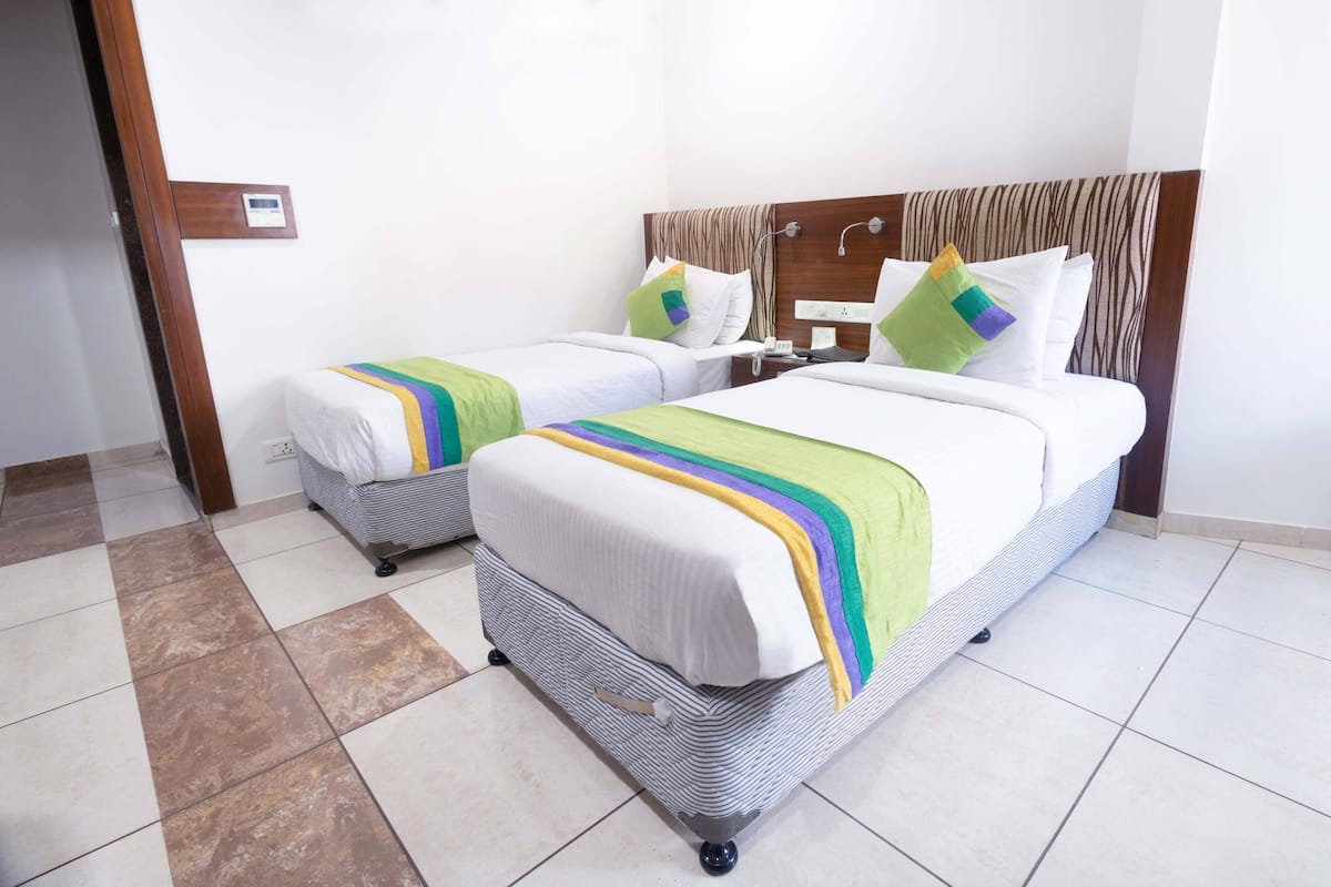 A hotel room with two beds, each with a striped bedspread and pillows.