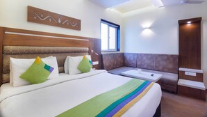 Una camera d'albergo con un letto grande, un divano, un tavolino e una ventola a soffitto.