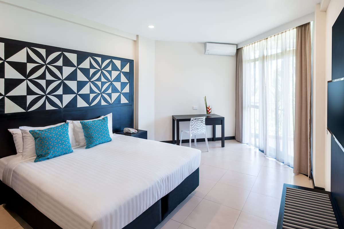 Une chambre d’hôtel moderne avec un grand lit, un bureau et une télévision.