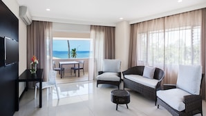 A modern living room with a balcony overlooking the sea, furnished with a sofa, chairs, and a small table.