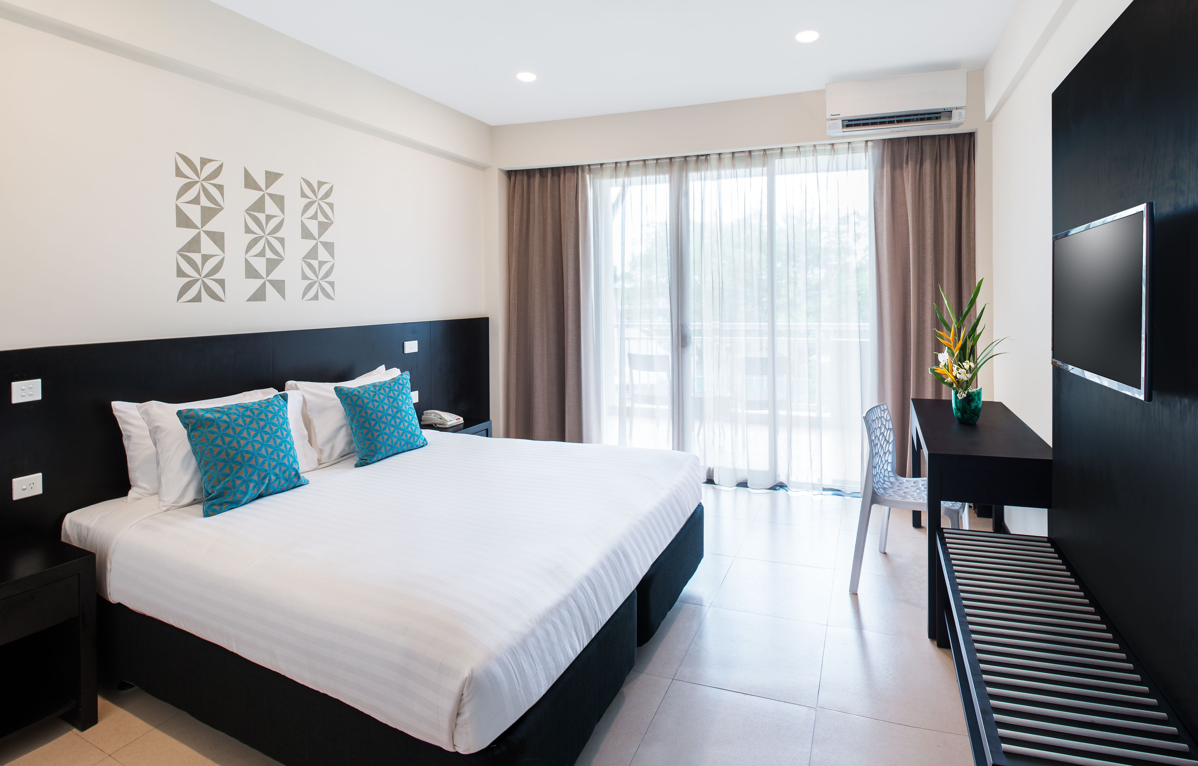 A modern hotel room with a large bed, a desk, and a chair.