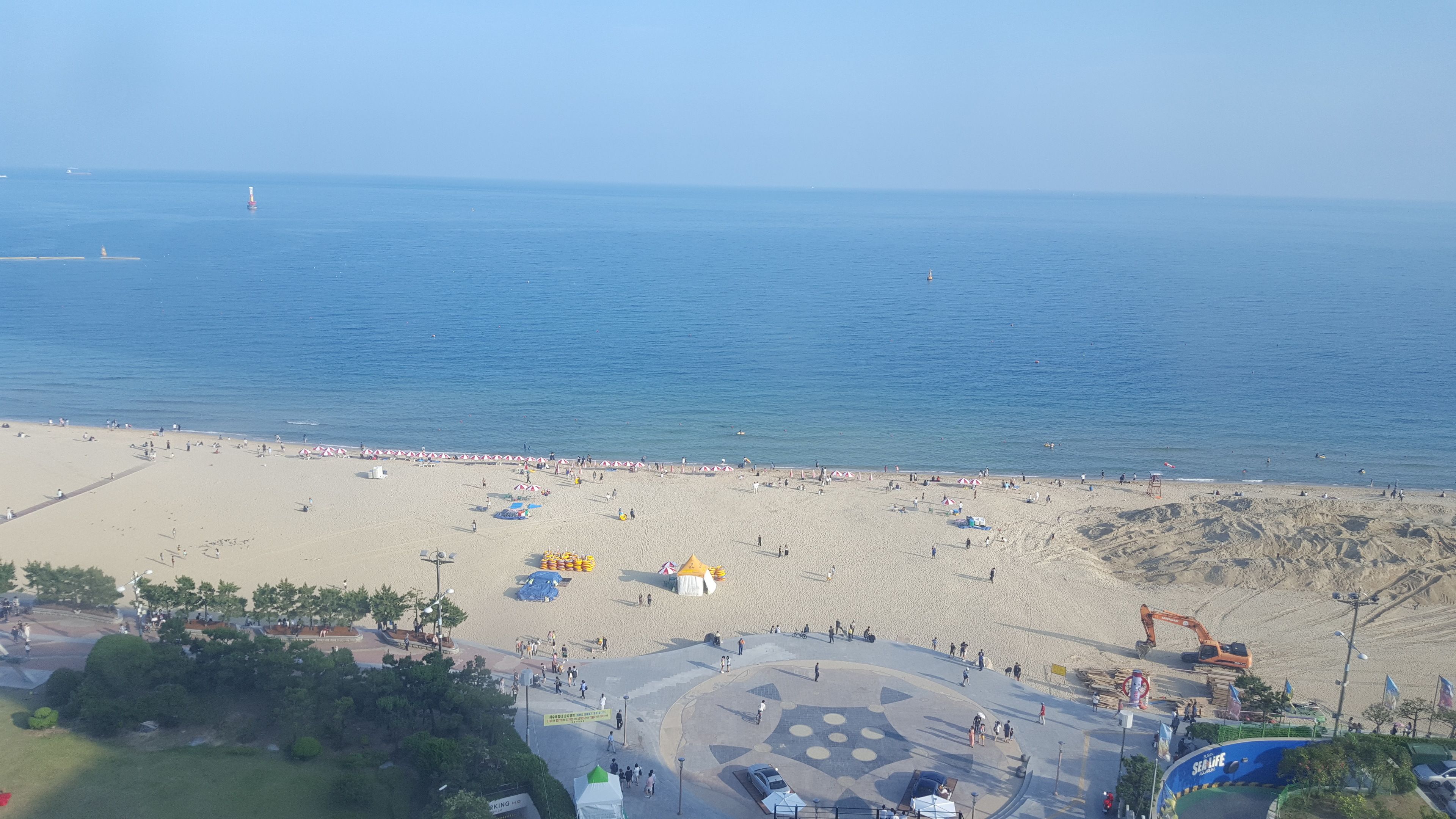 A beach with a sandy area, a few umbrellas, and a lifeguard tower.