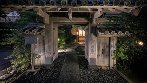A traditional wooden torii gate with a tiled roof, leading to a pathway with stepping stones. - Mizuno Ryokan (Karatsu)