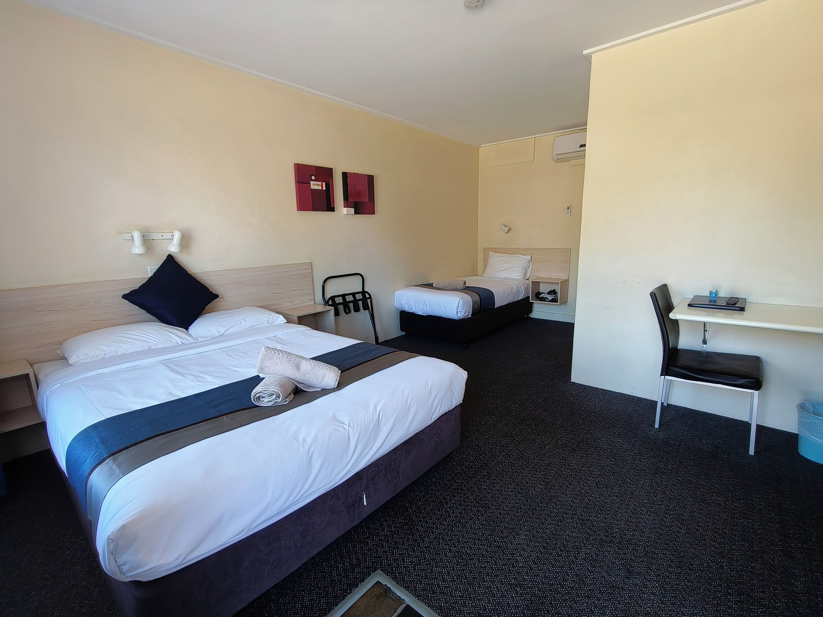 A hotel room with two beds, a desk, and a chair.