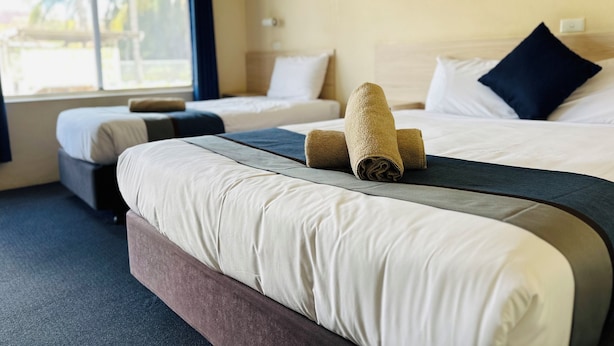 A hotel room with two beds, a large window, and a view of palm trees.