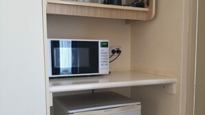 A compact kitchenette with a microwave and a small refrigerator. - Red Chief Motel (Gunnedah)