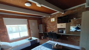 A hotel room with two beds, a desk, a microwave, and a TV.