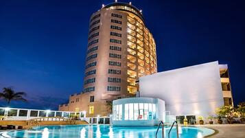 A hotel with a pool area, a large building with multiple balconies, and a modern structure with large windows.