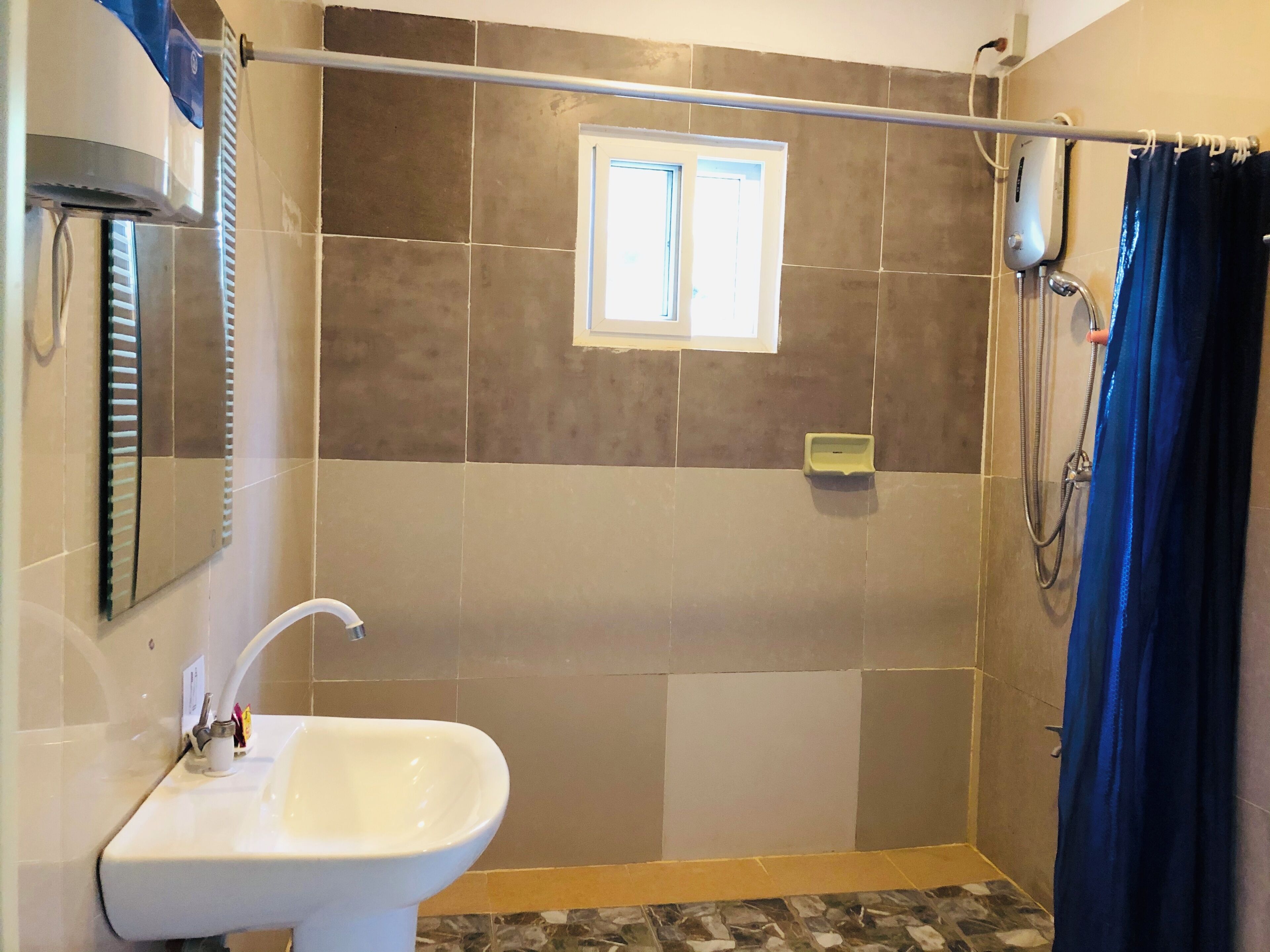 Een badkamer met een witte wastafel, een raam en een douchegedeelte.