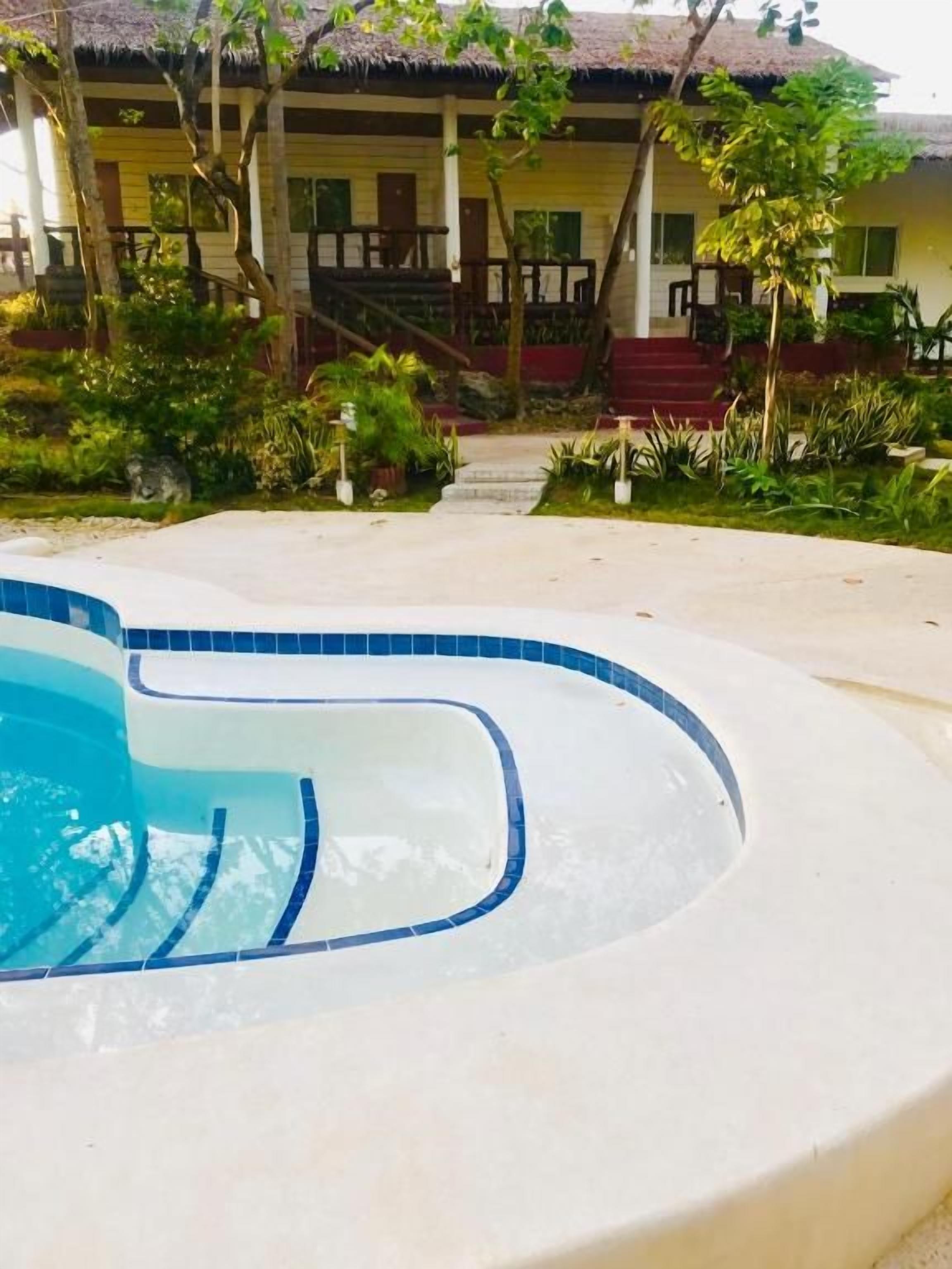 A swimming pool with a curved edge and a tiled border, surrounded by a concrete deck.