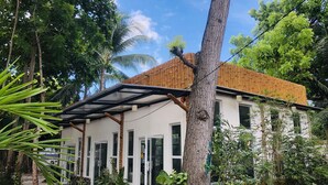 Un bâtiment moderne à la façade blanche, doté de grandes fenêtres et d’un espace extérieur abrité avec un toit en bois.