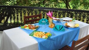 Una mesa al aire libre con mantel azul, varios platos y un jarrón decorativo.