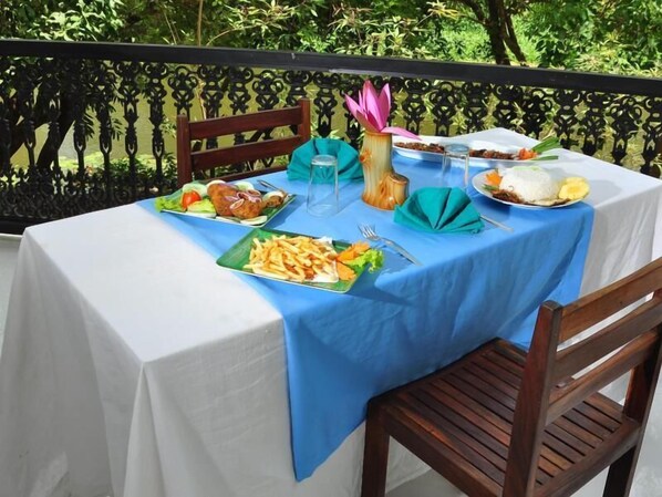 A table set outdoors with a blue tablecloth, various dishes, and a decorative vase.