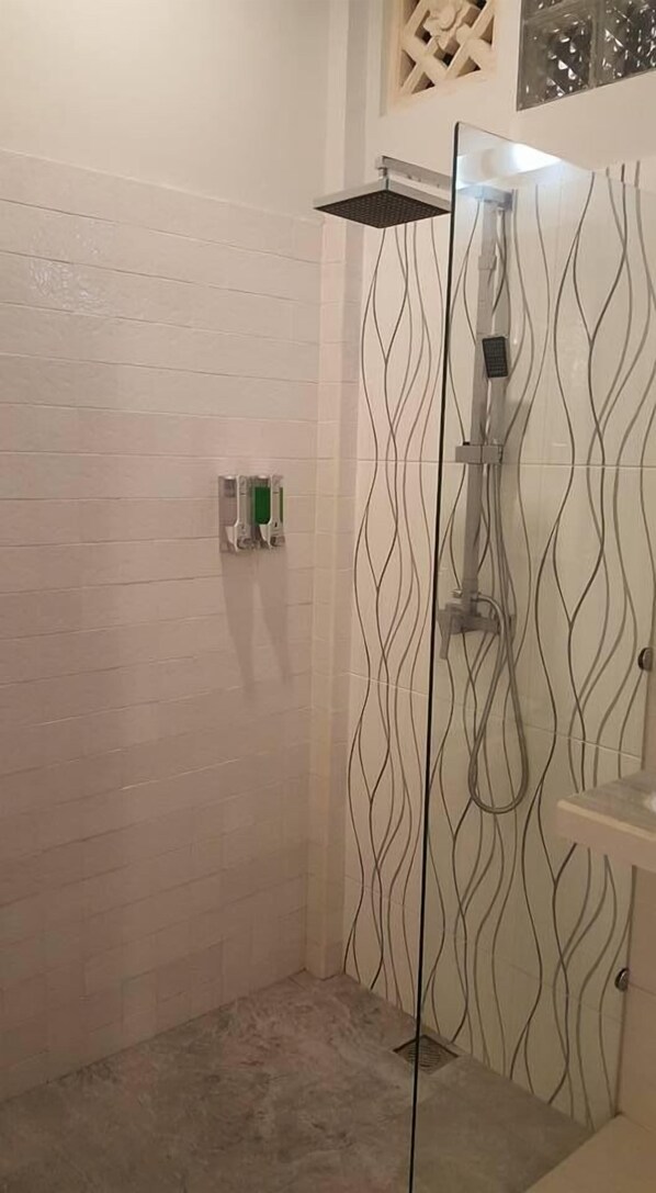A shower with a modern design, including a glass partition and a patterned wall. - Villa Kayla (Gili Trawangan)