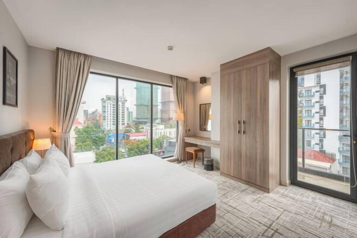 Habitación de hotel con una cama grande, un escritorio, un armario y vistas a la ciudad.
