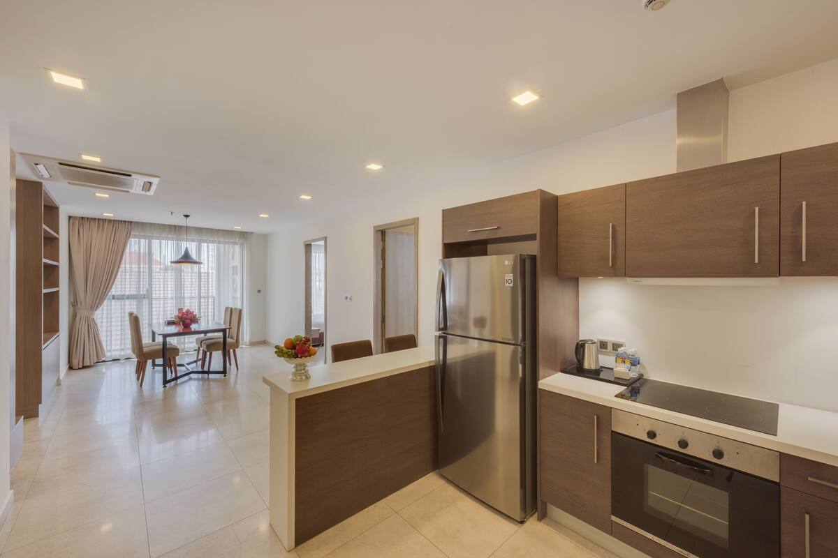 Una cocina moderna con una isla central, electrodomésticos de acero inoxidable y un comedor con mesa y sillas.