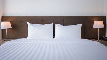 A neatly made bed with white bedding, a tufted headboard, and two bedside lamps on either side.