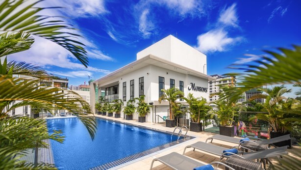 Un hotel con piscina, sillones de descanso y palmeras.