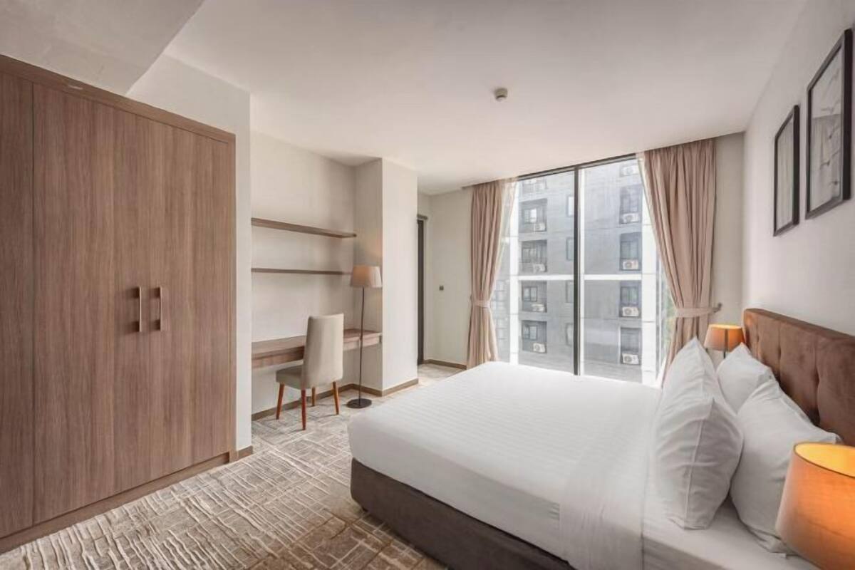 Habitación de hotel con una cama grande, un escritorio, un armario y vista a la ciudad.