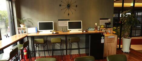Un área de bar moderna con dos monitores, un reloj y varias sillas verdes.