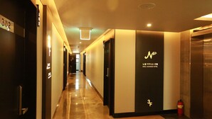 A hotel corridor with a modern design, featuring a clean, reflective floor and a combination of dark and light wall panels. - Noel Business Hotel (Busan)