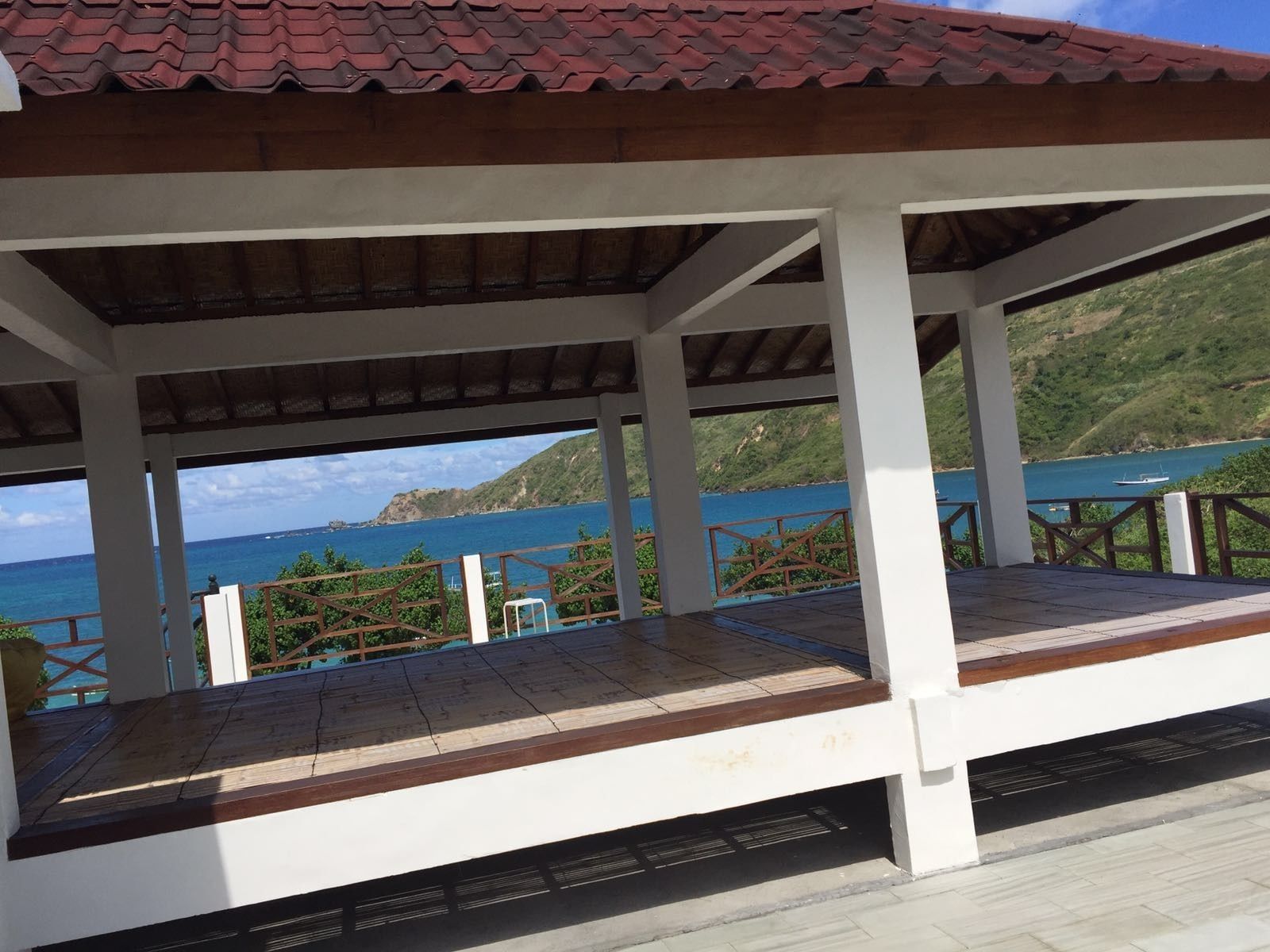 A covered outdoor area with a view of the sea and hills.