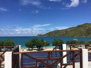 A coastal view with a wooden deck, a sandy beach, and a clear blue sky. - Friends Beach Hotel (Kuta)