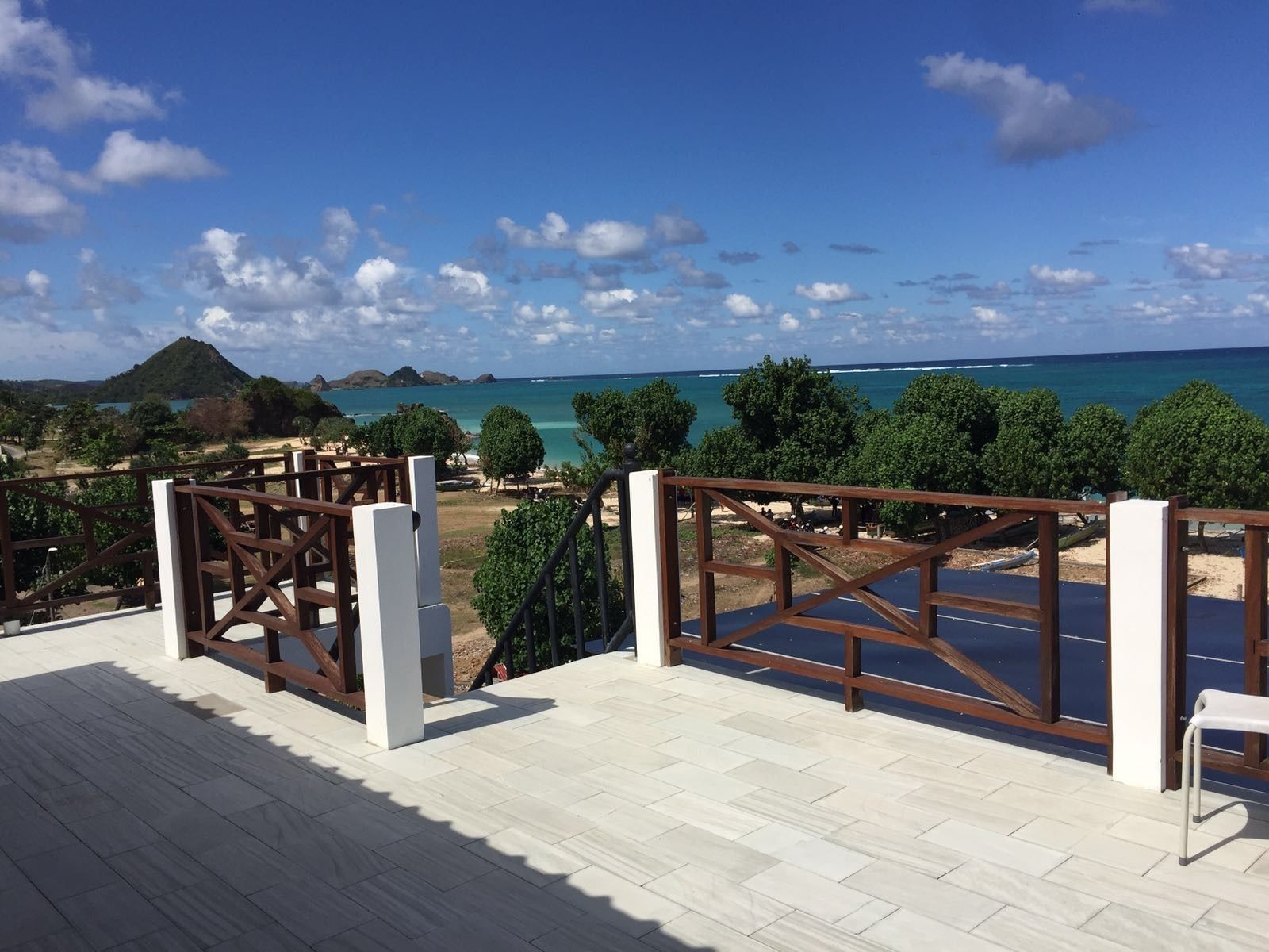 Una terraza de madera con vista al océano y un paisaje montañoso.