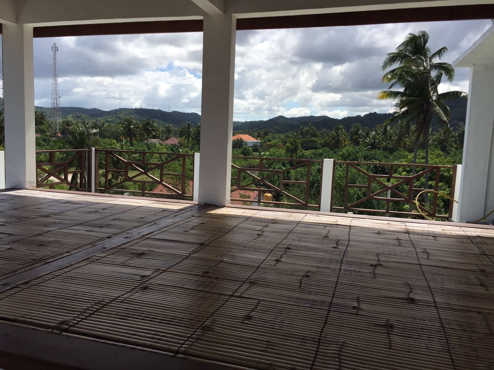 A covered outdoor area with a view of a mountainous landscape and palm trees.