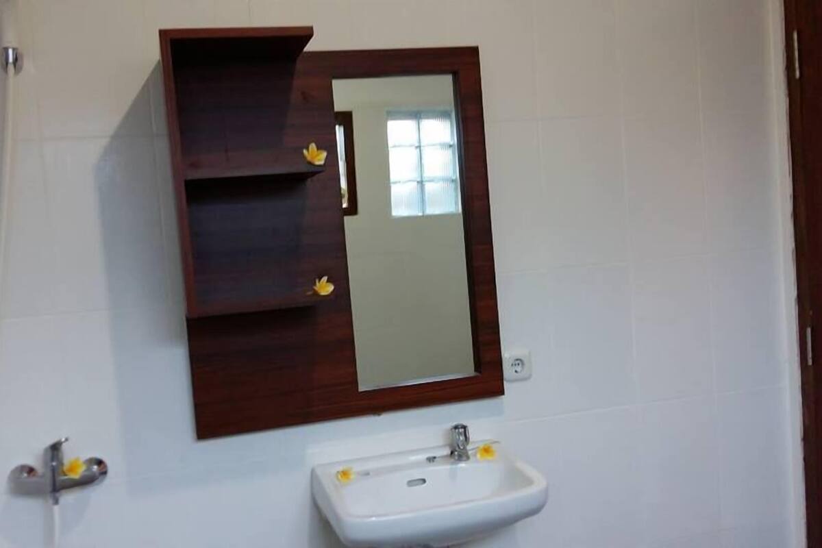 A bathroom with a white sink, a mirror, and a wooden cabinet.