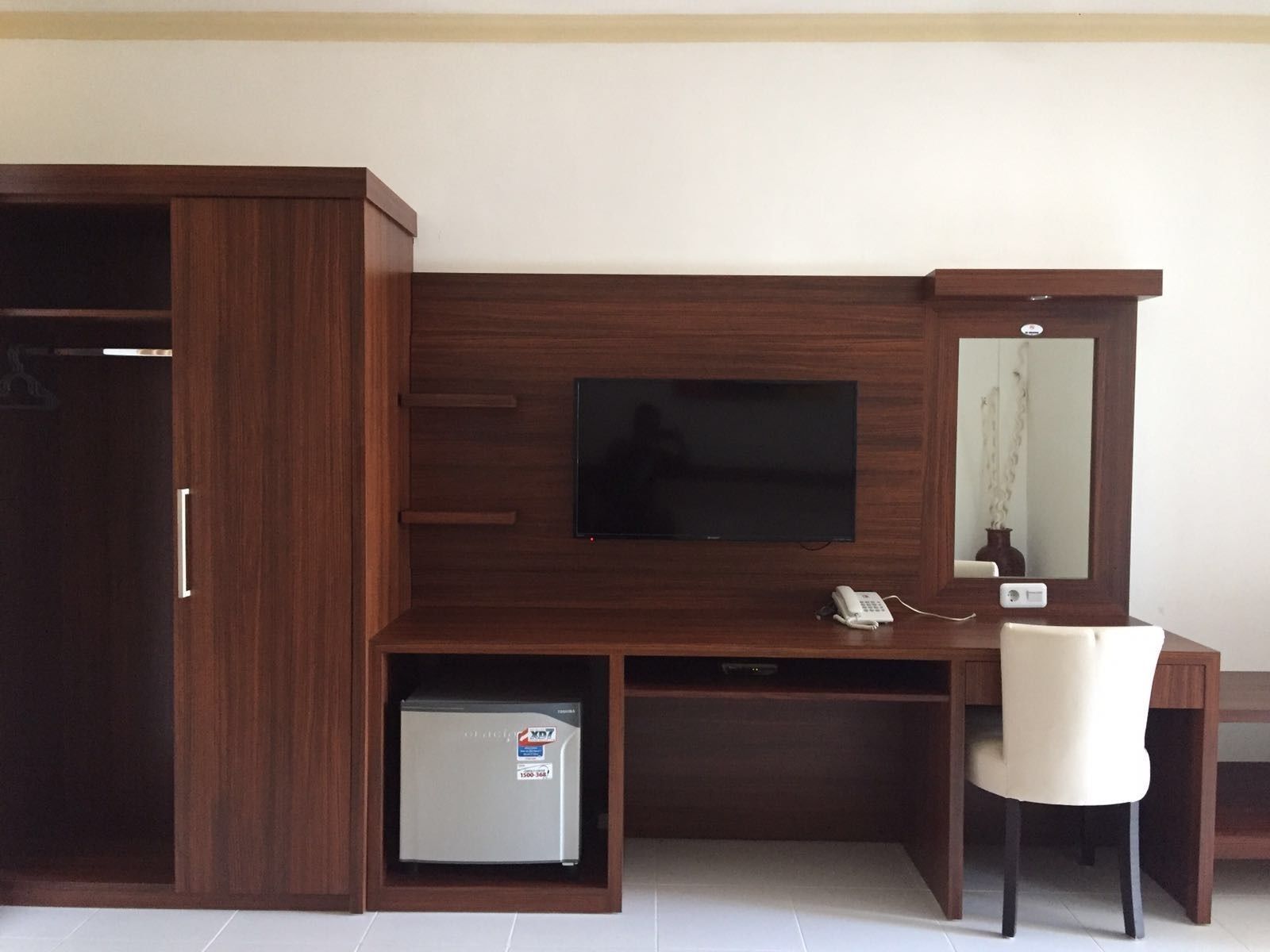 Een hotelkamer met een houten bureau, een televisie, een telefoon en een kleine koelkast.
