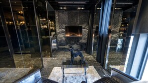 Un interior moderno con una pared de piedra, una chimenea y dos sillones de cuero.