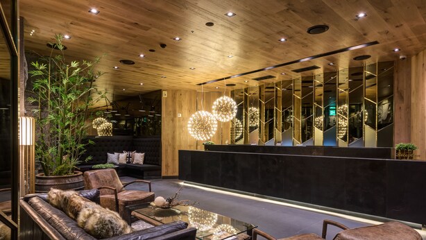 Un lobby moderno con mostrador de recepción, zona de estar e iluminación decorativa.
