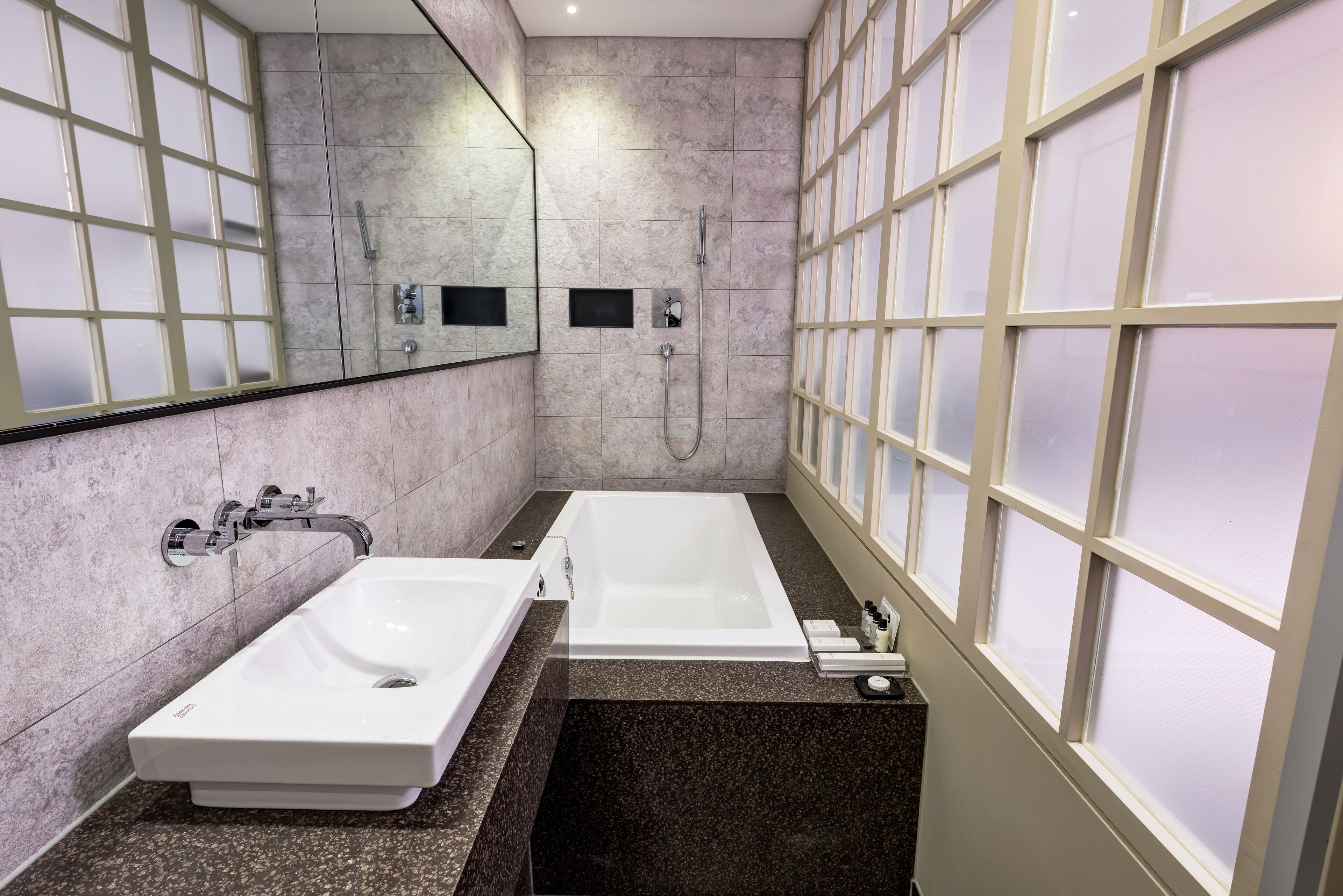 Un baño moderno con dos lavamanos, una bañera y un espejo grande.