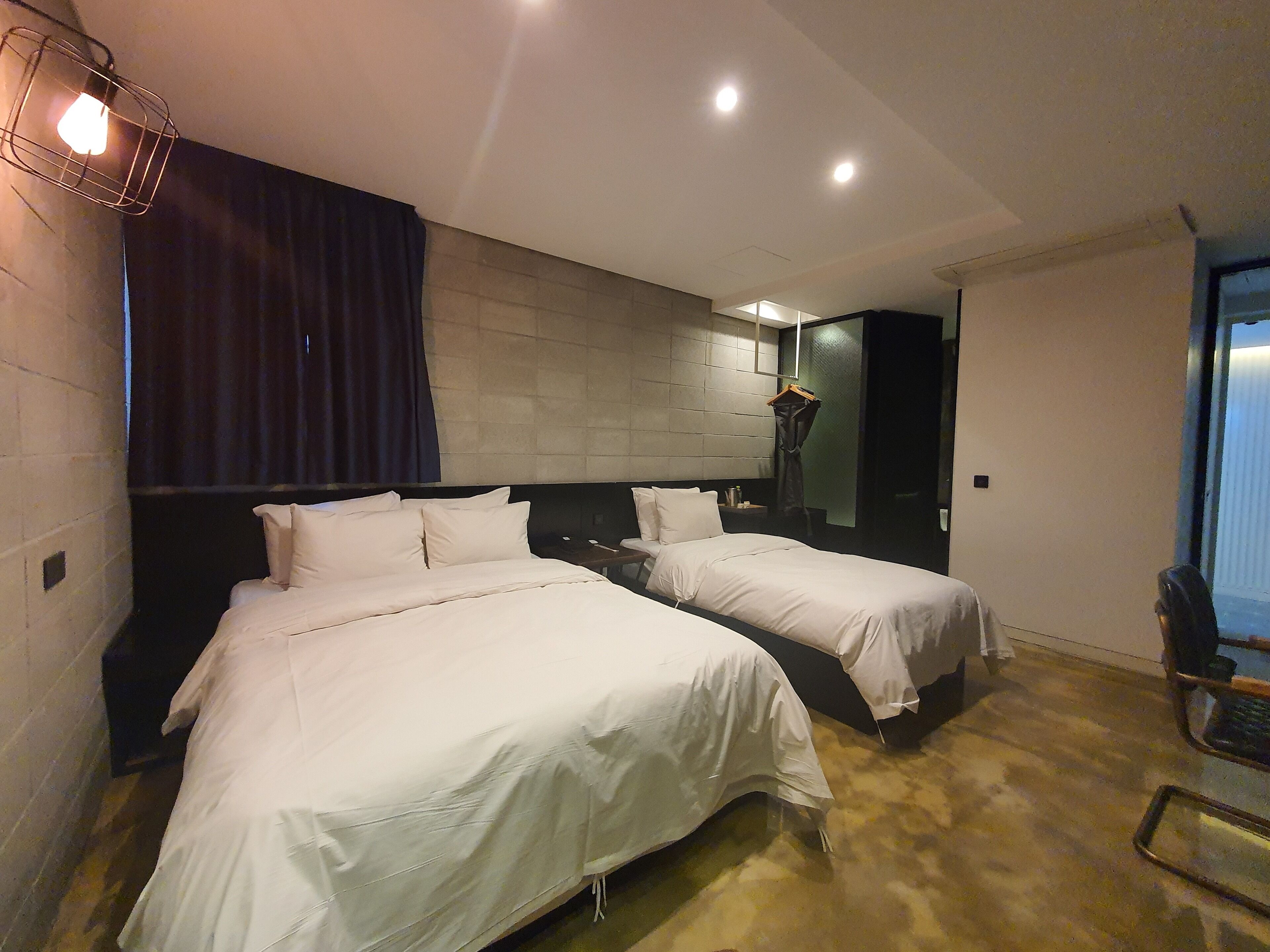 A hotel room with two beds, a large mirror, and a hanging light fixture.