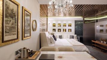 A modern hotel room with a large bed, a desk with a laptop, and a chandelier.