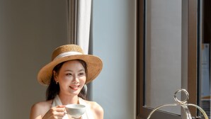 A woman seated at a round table with a tiered dessert stand, a teapot, and various pastries and fruits. - Marriott Executive Apartments Bangkok, Sukhumvit 101 (Bangkok)