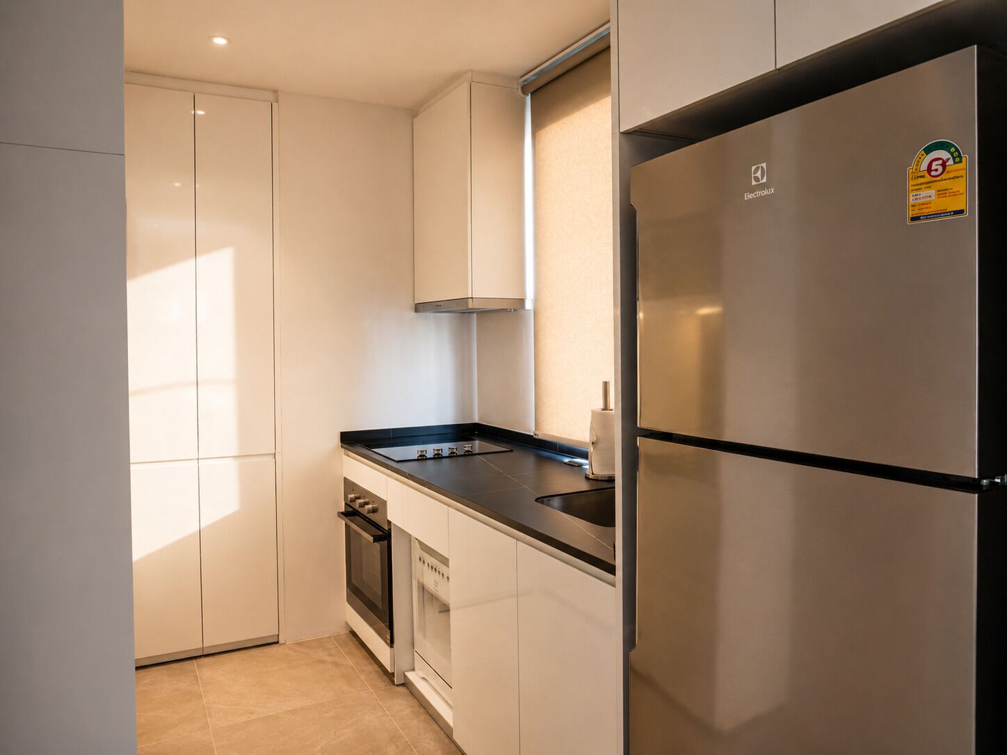 A modern kitchen with white cabinets, a stainless steel refrigerator, and a built-in oven.